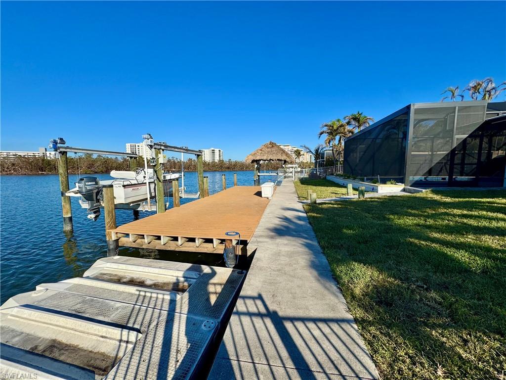 Dock area with a lanai, a yard, and a water view