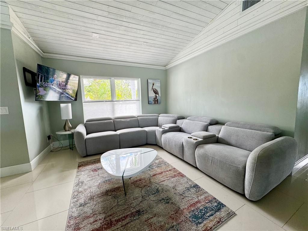 Tiled living room with lofted ceiling, wood ceiling, and ornamental molding