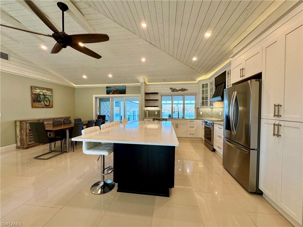 Kitchen featuring a large island, wooden ceiling, stainless steel appliances, lofted ceiling, and white cabinets