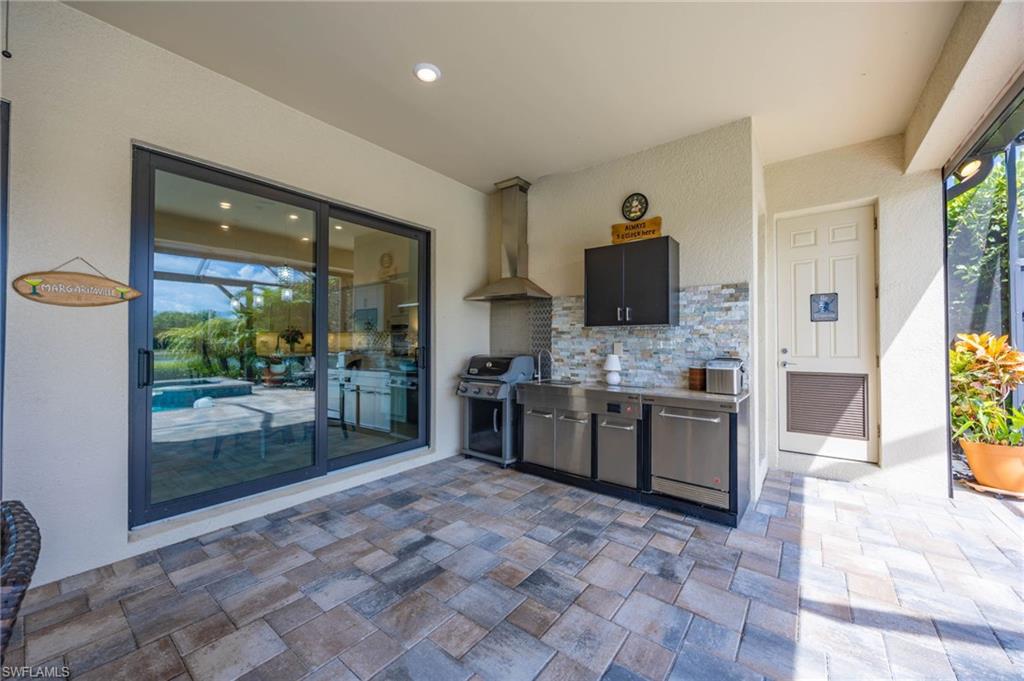 Rear covered lanai  patio featuring a built-in outdoor kitchen with storage closet and pool bath