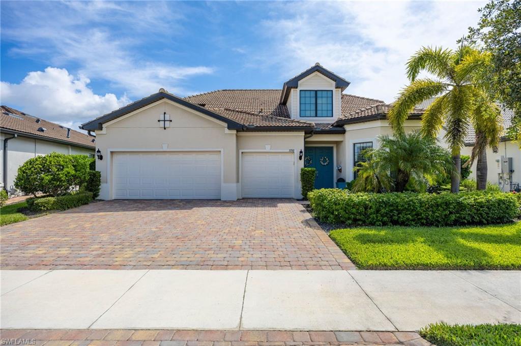 Stately curb appeal featuring a 3 car extended garage, mature landscaping,  tile roof, stucco exterior, and a paved driveway