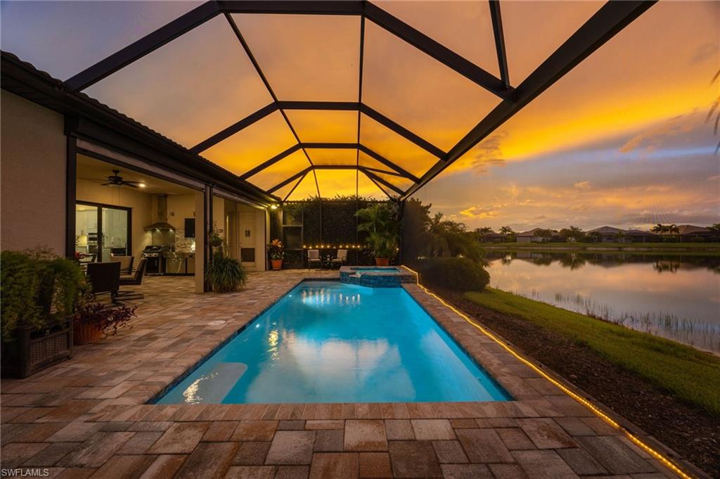 Sunset from the enclosed pool area and covered outdoor kitchen/ dining  area, all overlooking a tranquil body of water