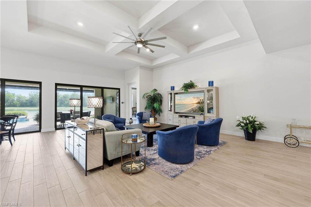 Spacious interior great room  featuring a tiered tray ceiling with a ceiling fan, recessed lighting, and light tile flooring, great space to entertain