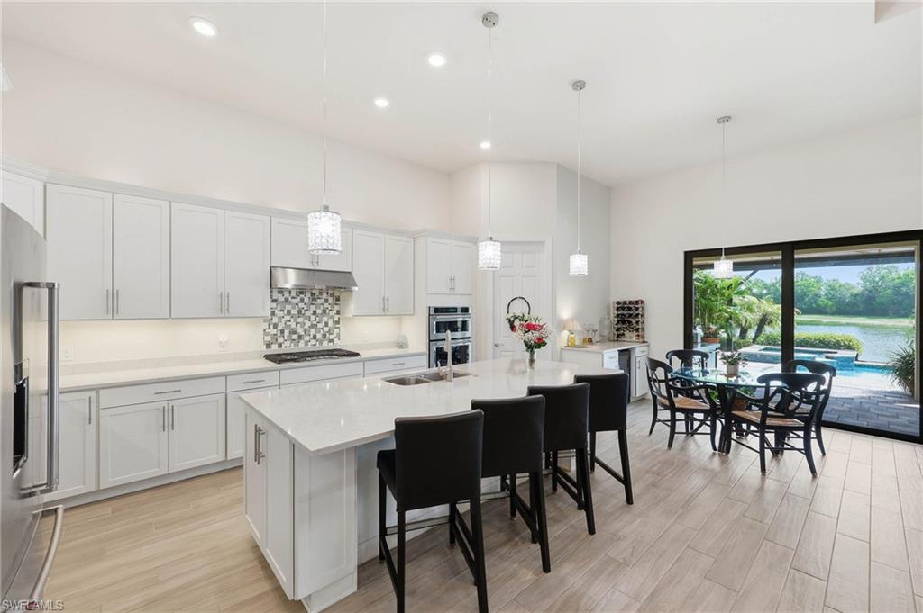 Contemporary kitchen featuring white shaker cabinetry, quartz countertops, a mosaic tile backsplash, recessed lighting, and wood-tile flooring