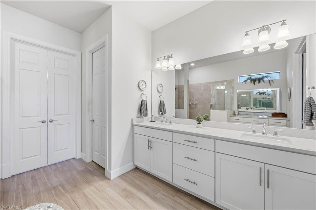 Expansive vanity with dual undermount sinks, white cabinetry, private water closet and double doors into your spacious walk in closet