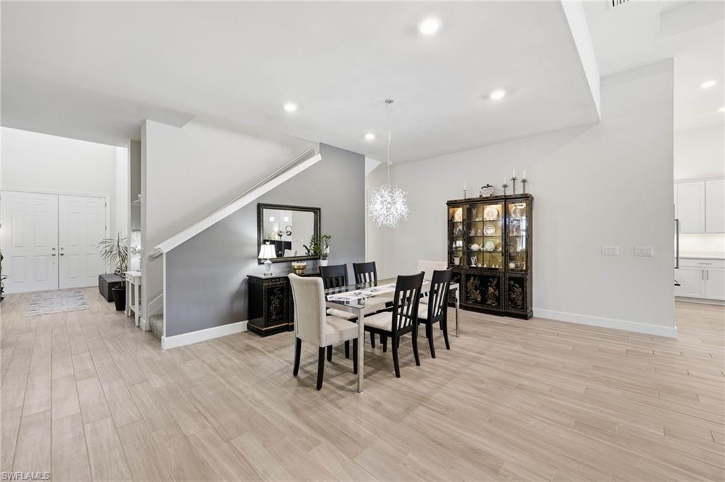 Spacious interior dining room area featuring light tile flooring, recessed lighting, and staircase leading to additional living space