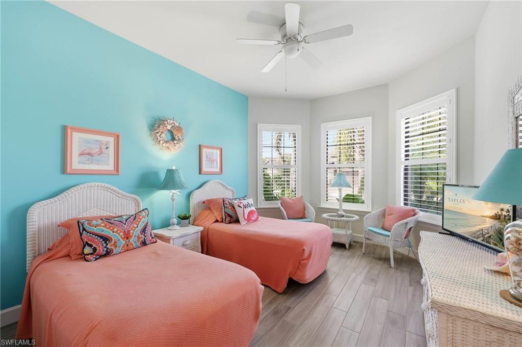Guest Bedroom #1  featuring a vibrant accent wall, tile flooring, windows with white plantation shutters