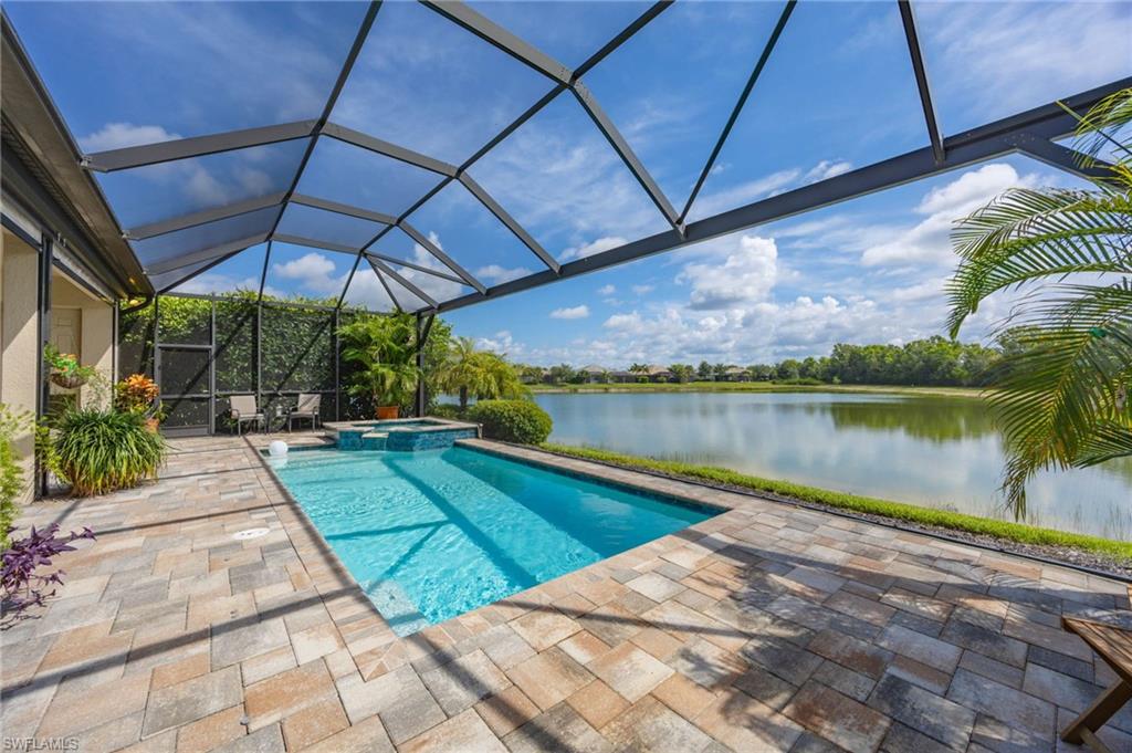 Screened outdoor swimming pool with an integrated spa, set on a paver patio with private lake views