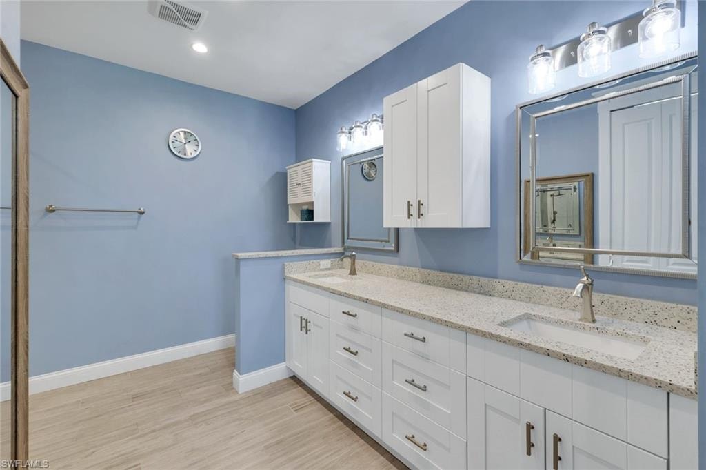 Dual vanity with white cabinetry, speckled countertops, and undermount sinks