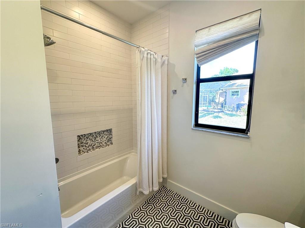 Bathroom featuring shower / tub combo, tile patterned flooring, and toilet