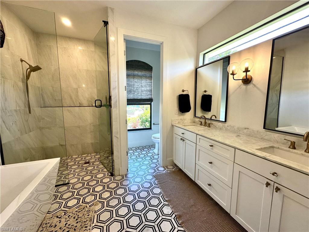 Bathroom featuring an enclosed shower, vanity, tile patterned flooring, and toilet