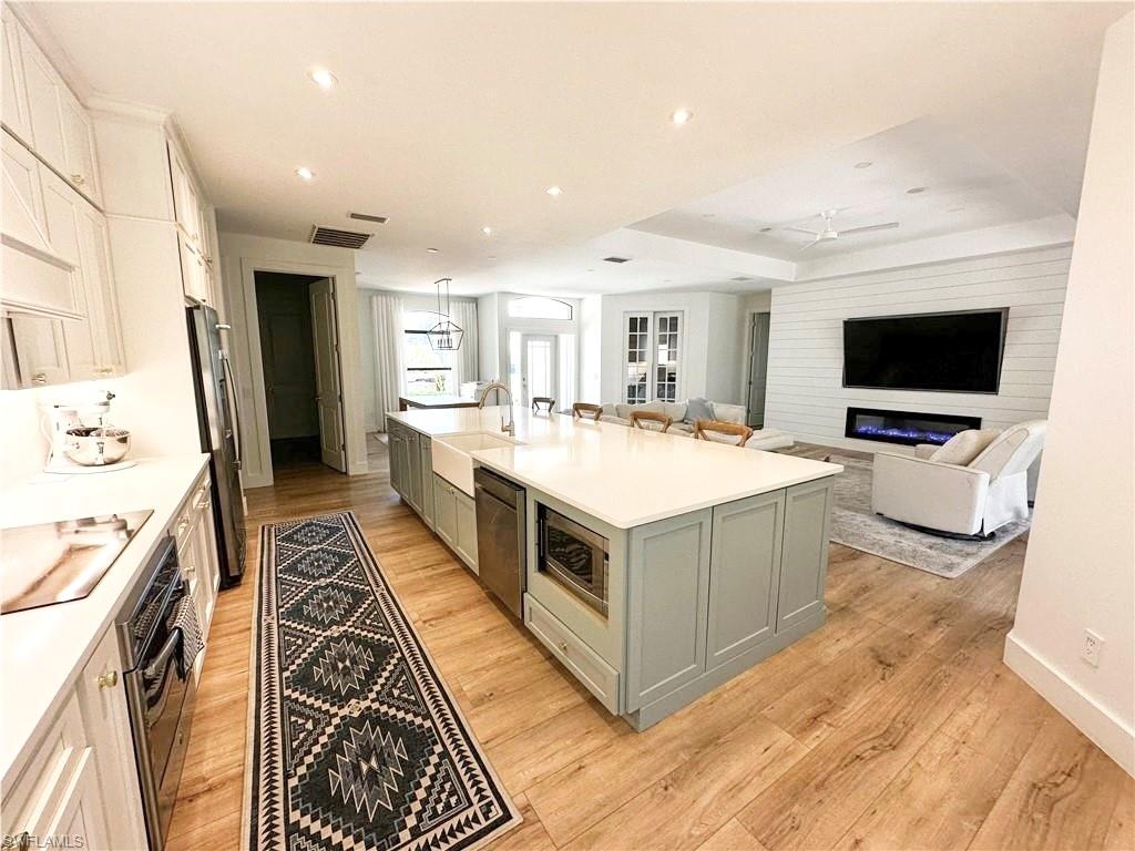 Kitchen featuring sink, stainless steel appliances, light hardwood / wood-style floors, an island with sink, and white cabinets