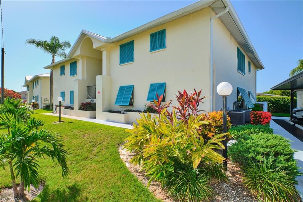 Multi-story building featuring a light-colored stucco exterior with contrasting blue louvered window coverings