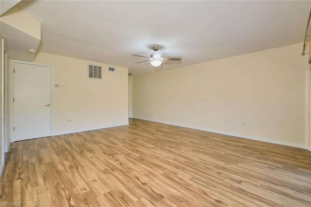 Spacious interior room featuring wood-finish flooring, a ceiling fan with integrated lighting, and neutral-toned walls