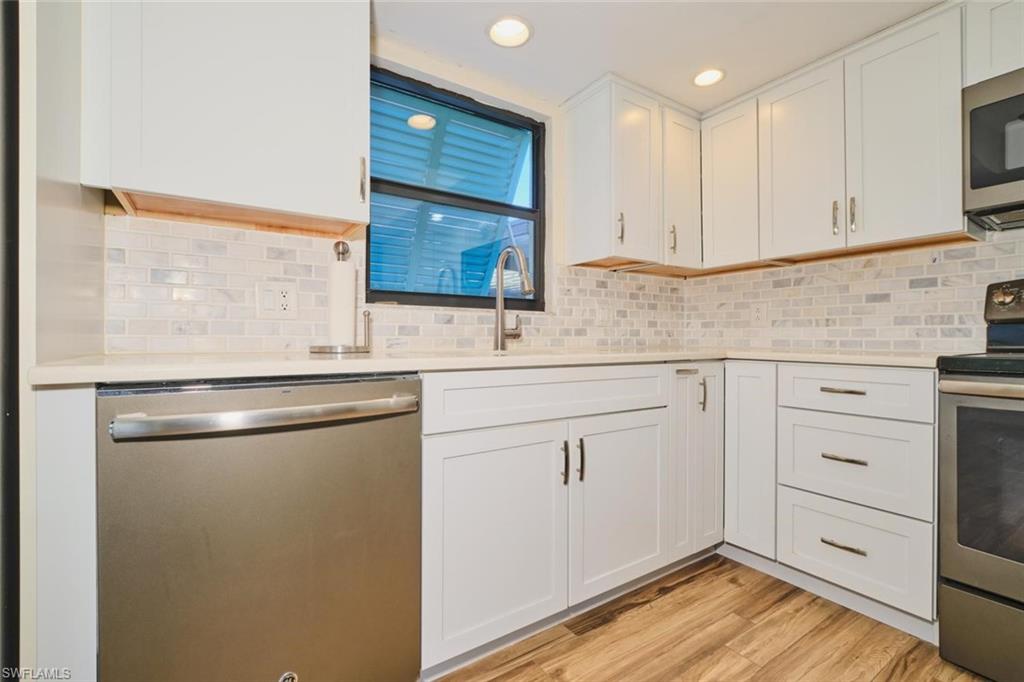 Modern kitchen featuring white shaker cabinetry, stainless steel appliances, light countertops, and a subway tile backsplash