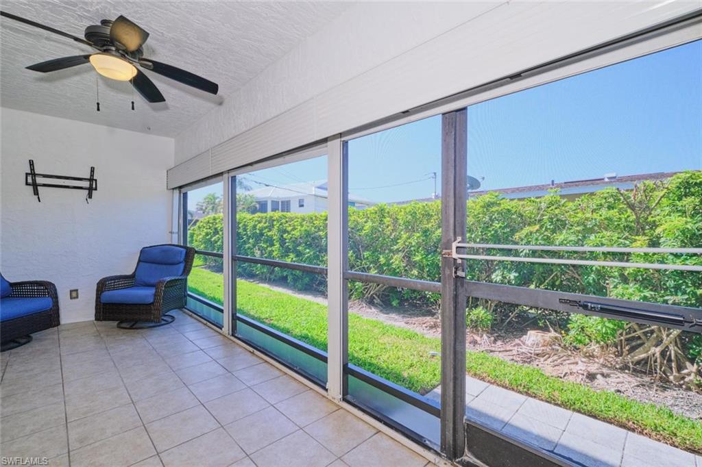 Screened lanai featuring large sliding panels, tile flooring, a sloped ceiling, and a ceiling fan