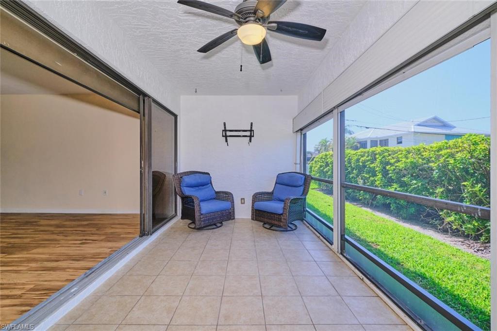 Screened patio featuring ceramic tile flooring, a ceiling fan with integrated lighting, and a wall-mounted bracket