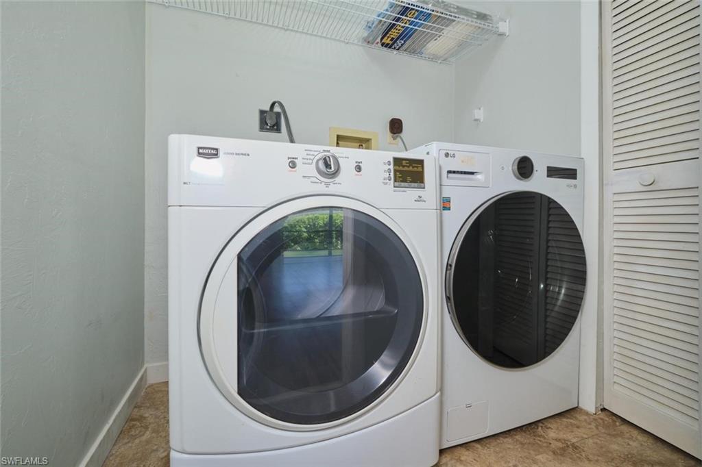 Laundry Closet featuring a front-loading washer and dryer, wire shelving, and louvered bifold doors