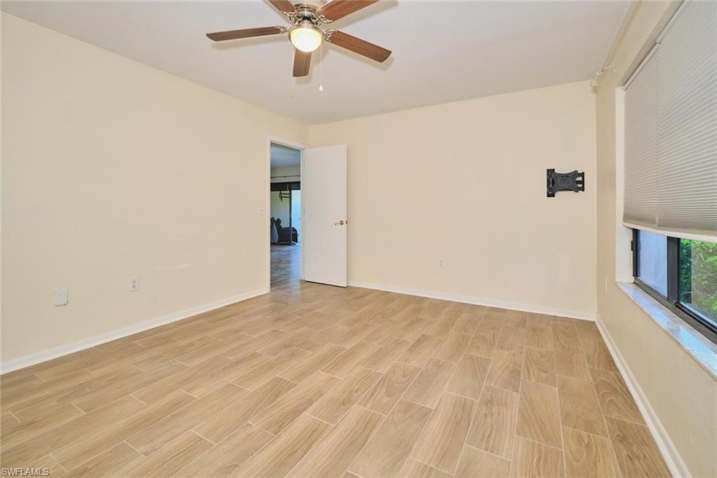 Spacious room featuring wood-finish tile flooring, a ceiling fan, and window with horizontal blinds