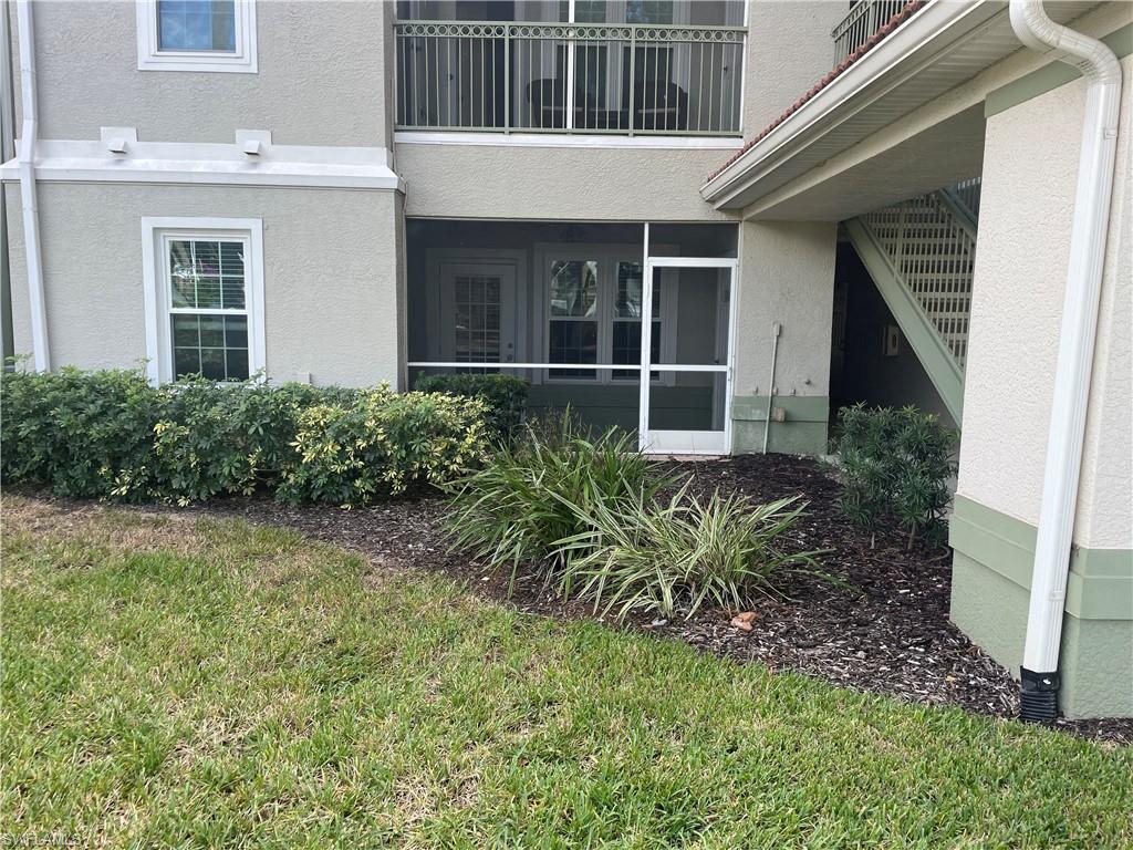 Entrance to property with a sunroom, stucco siding, and a lawn