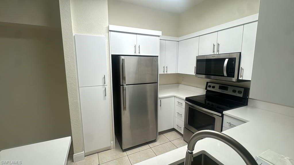 Kitchen featuring white cabinetry, stainless steel appliances, white countertops, and tile flooring