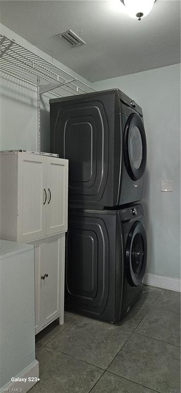 Laundry area with stacked washer / drying machine and tile patterned flooring