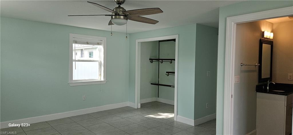 Unfurnished bedroom featuring light tile patterned floors, a ceiling fan, and a closet