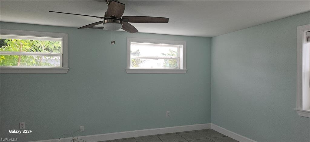 Tiled spare room with baseboards and ceiling fan