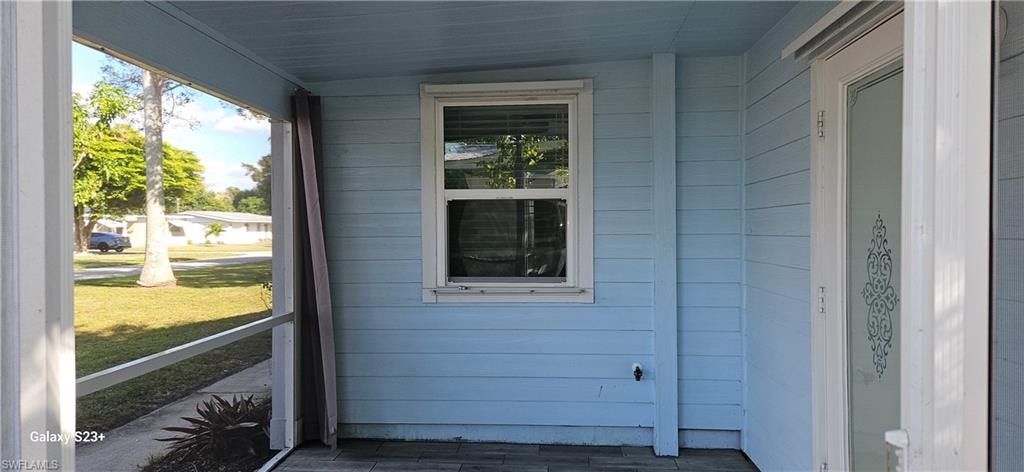 View of front exterior entry with covered porch and a lawn
