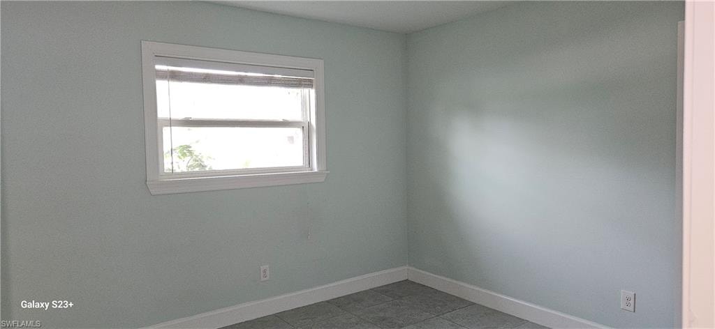 Empty room featuring baseboards and light tile patterned floors