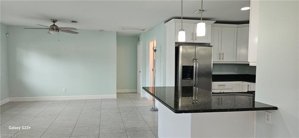 Kitchen with stainless steel fridge with ice dispenser, white cabinetry, dark stone countertops, and a peninsula