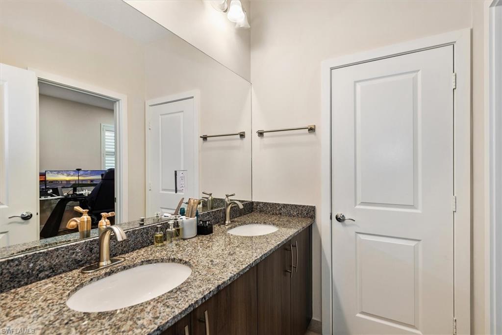 Jack-n-Jill with dual vanity with granite countertop, integrated sinks, brushed nickel faucets, and rich wood-finish cabinetry