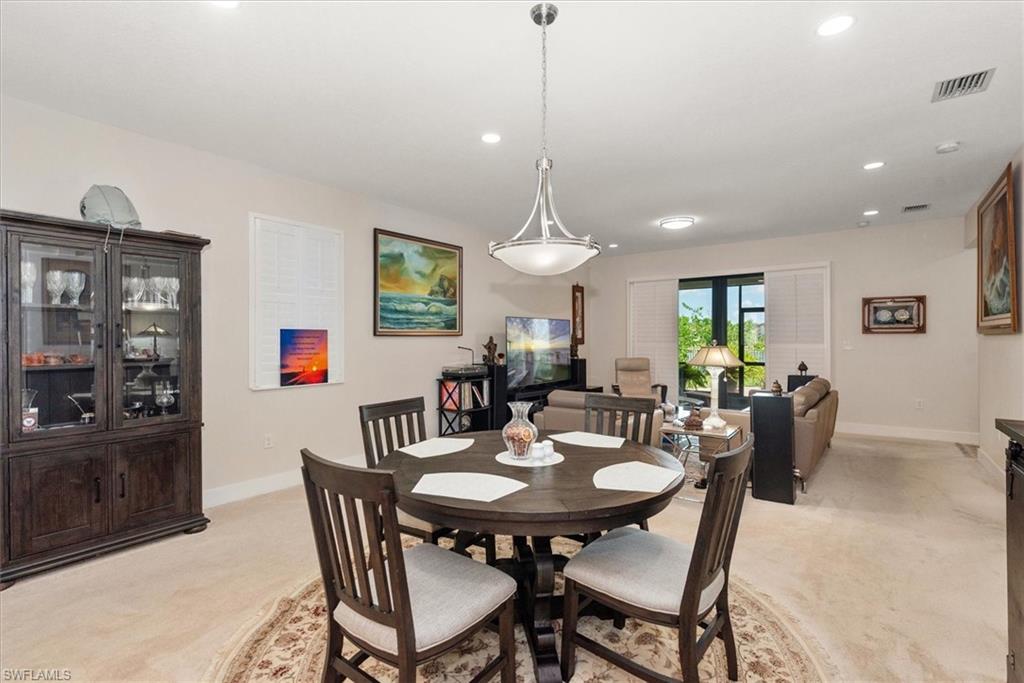 Open-concept living area featuring light-toned carpeting, a modern pendant light fixture, and recessed lighting