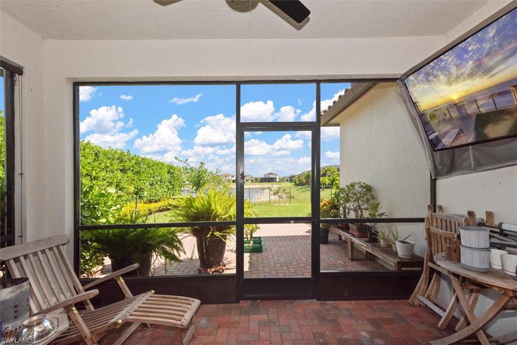 Screened lanai with brick flooring, overlooking a green landscape with a distant body of water
