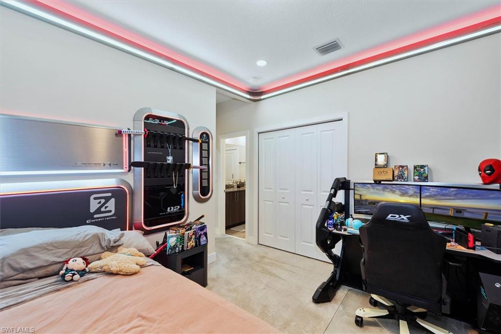 Bedroom featuring tray ceiling with integrated lighting, bi-fold closet doors, and wood-finish flooring