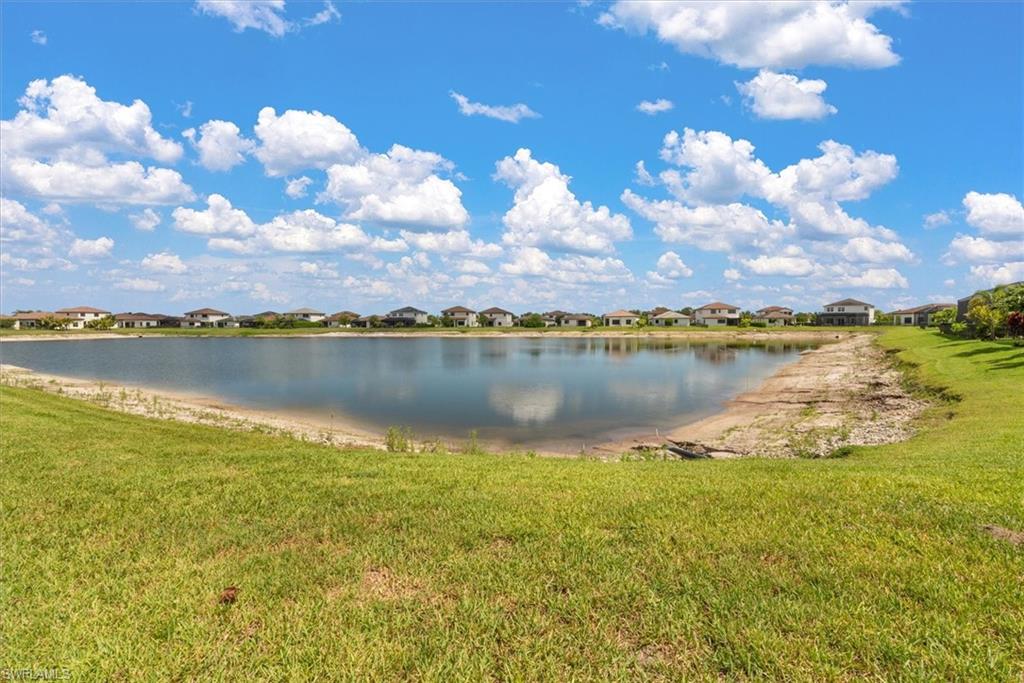 Expansive lakefront property featuring a broad water body, surrounding green space, and a distant residential backdrop
