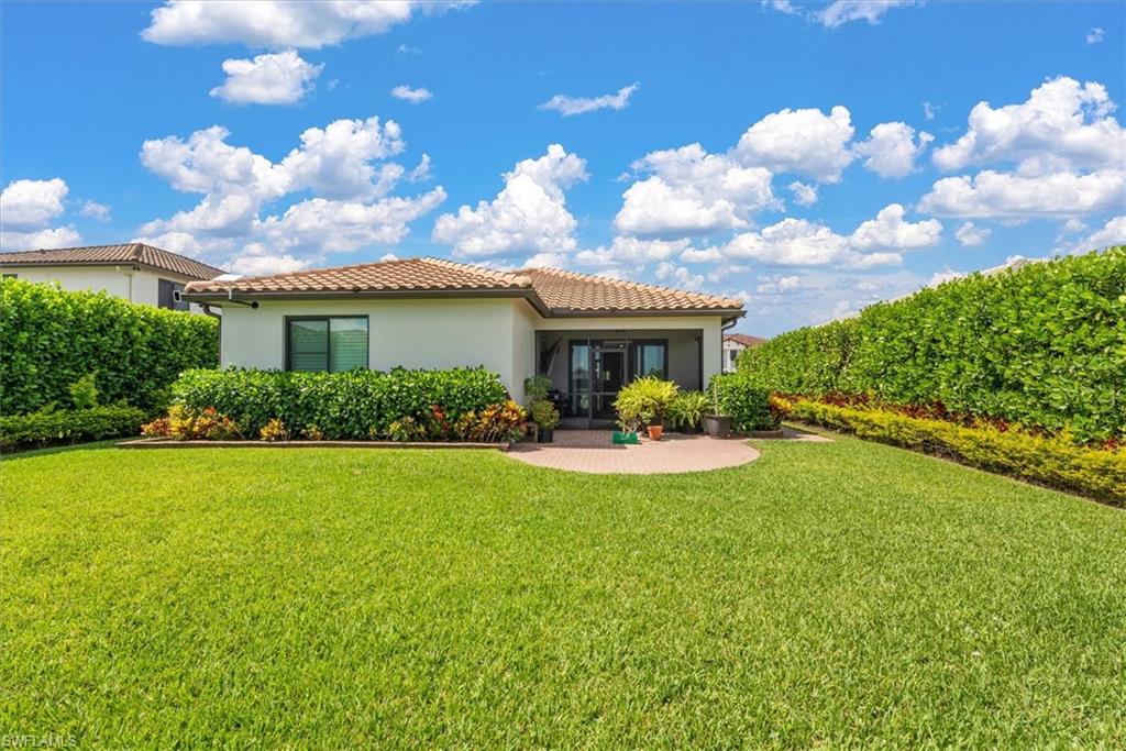 Expansive green lawn with mature privacy planter hedges and a rear screened patio