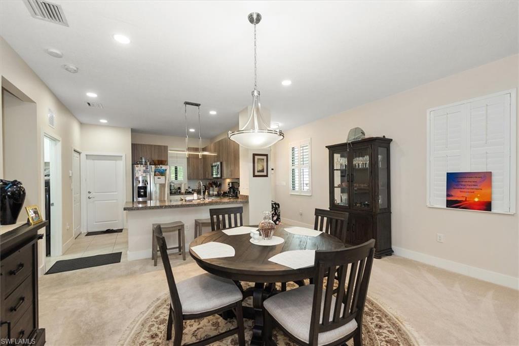 Open-concept dining area featuring recessed lighting, a contemporary chandelier, and carpeting