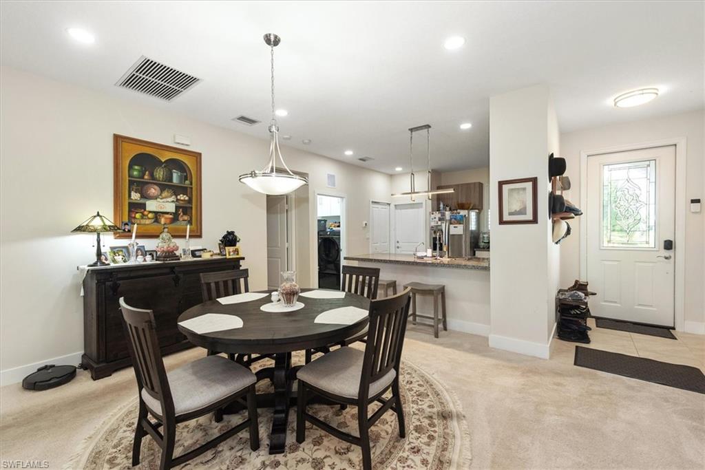 Open-concept living space featuring a dining area with a contemporary chandelier, recessed lighting, and light-toned carpeting