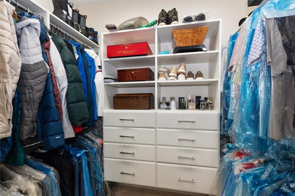 Custom closet system in mast bedroom featuring white shelving units, built-in drawers with modern pulls, and integrated hanging rods for garment storage