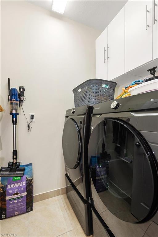 Dedicated laundry area featuring a premium Samsung washer & dryer, upper cabinetry with modern hardware, and tile flooring