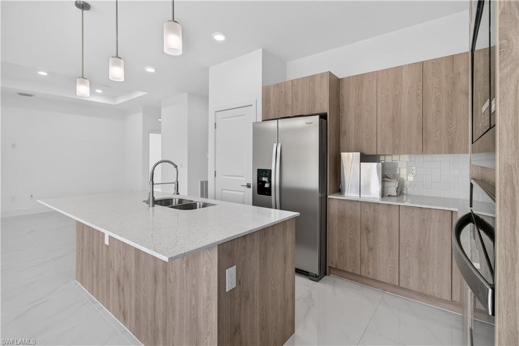 Kitchen island featuring a dual-basin stainless steel sink, gooseneck faucet, and light-toned countertop