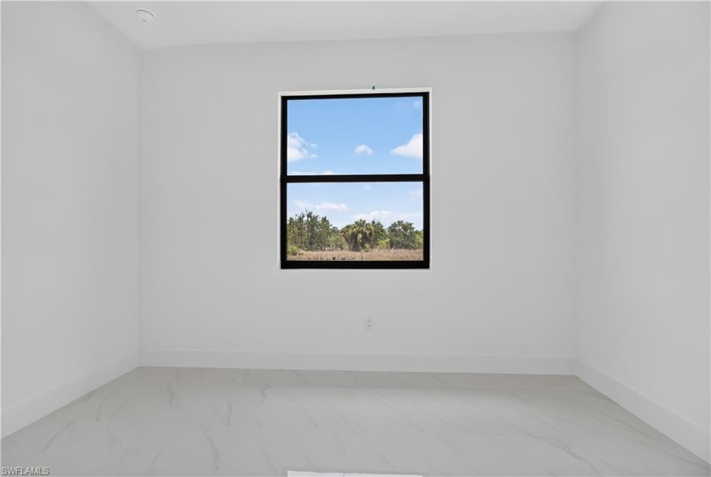 Minimalist room featuring a large black-framed window, recessed ceiling lighting, and light-toned tile flooring