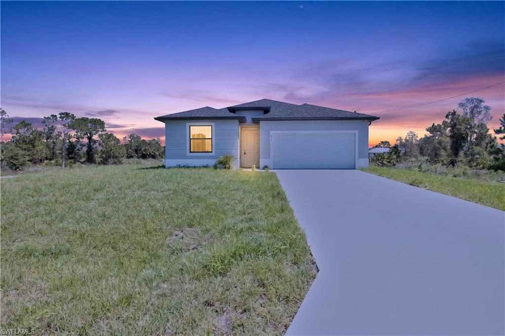 Single-story residence featuring light blue siding, a dark shingle roof, an attached garage, and a concrete driveway