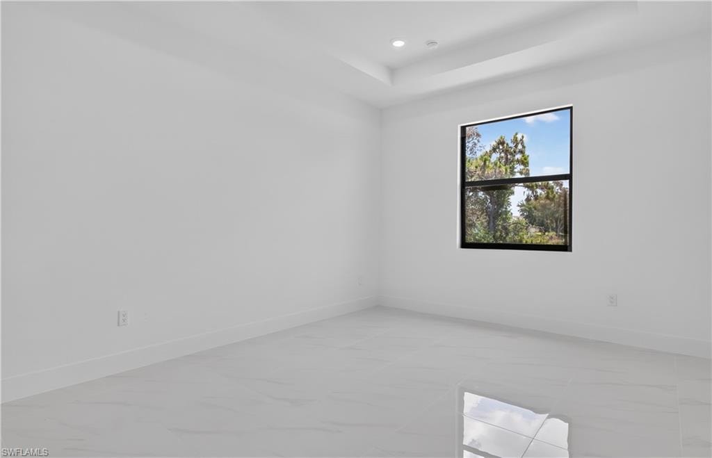 Neutral interior featuring a black-framed window, recessed lighting, a tray ceiling, light-toned walls, and wood-finish flooring