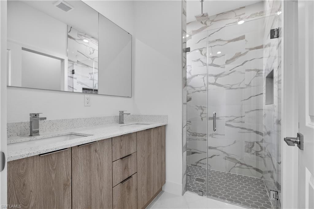 Bathroom featuring a dual vanity with a speckled countertop, undermount sinks, and a wood-finish cabinet