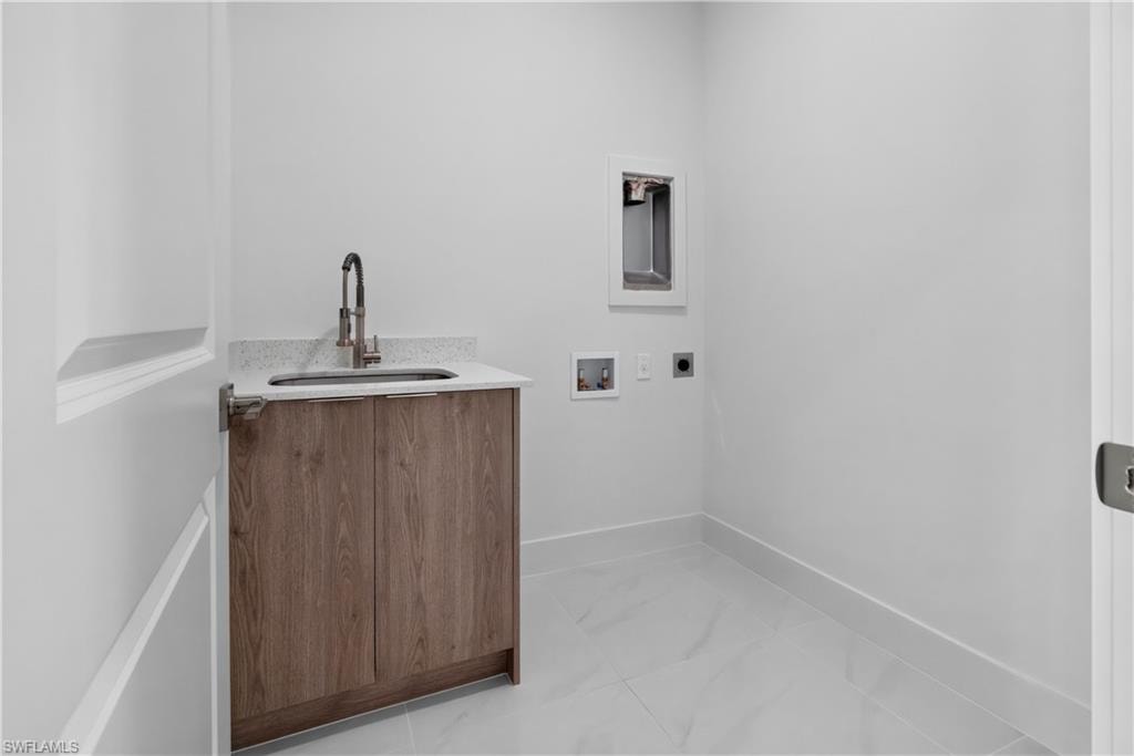 Utility room featuring a wood-finish vanity with an undermount sink, a light-toned countertop, and tile flooring