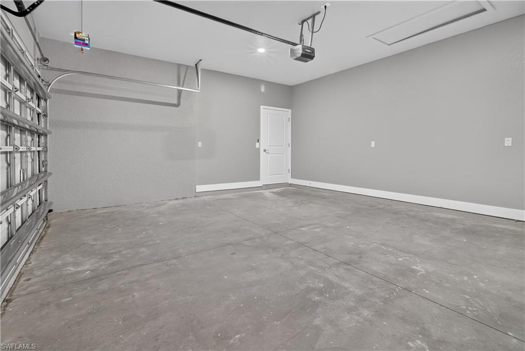 Spacious garage featuring a concrete floor, light gray walls, white trim, and a white interior door