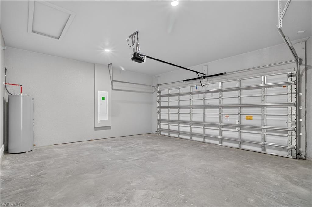 Spacious garage featuring a concrete floor, automatic garage door opener, and a water heater