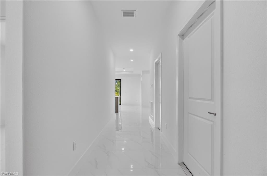 Hallway featuring recessed lighting, white walls, white doors, and polished tile flooring